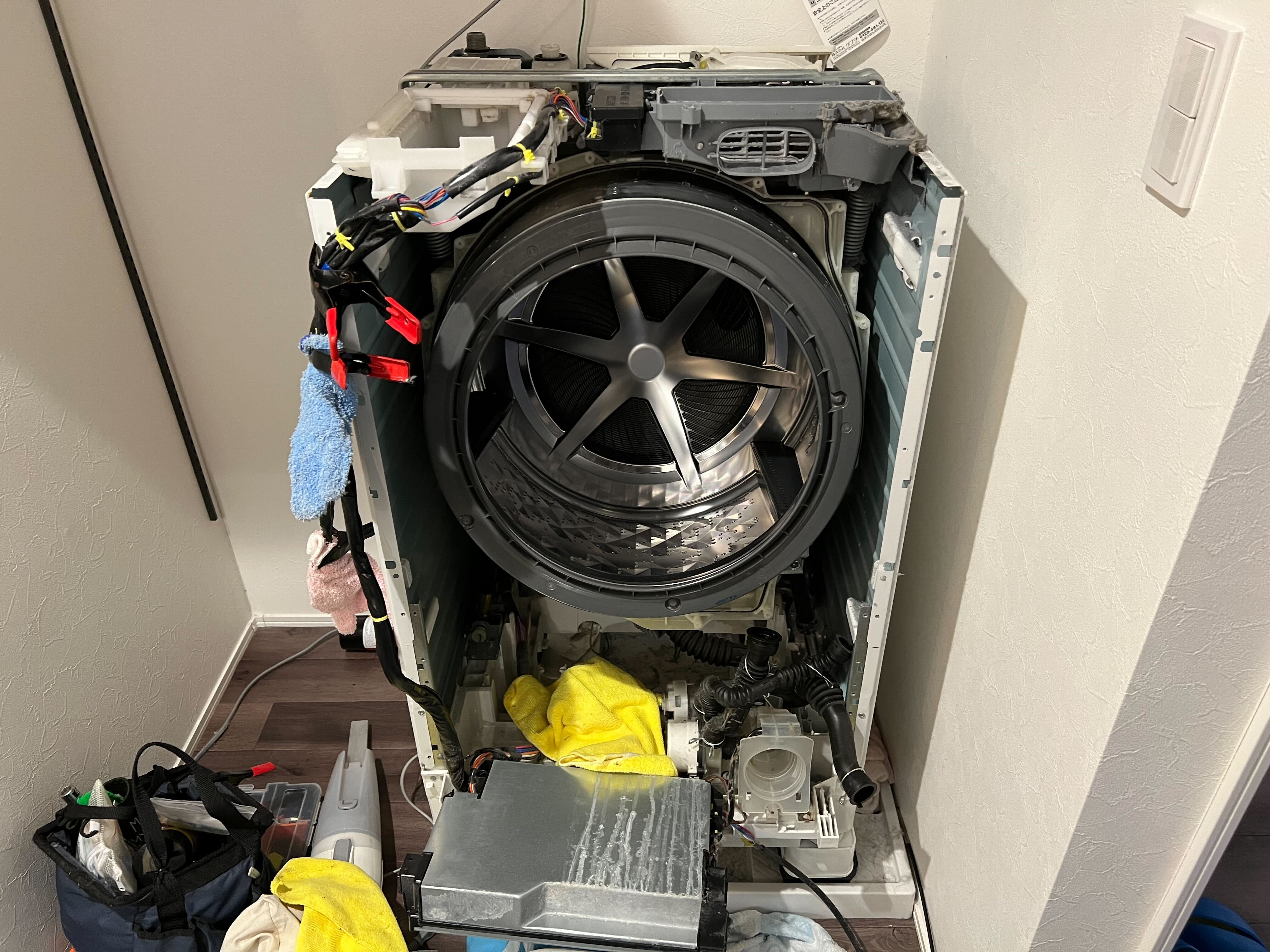 ドラム式洗濯機が分解されて中身が丸裸になっている写真。