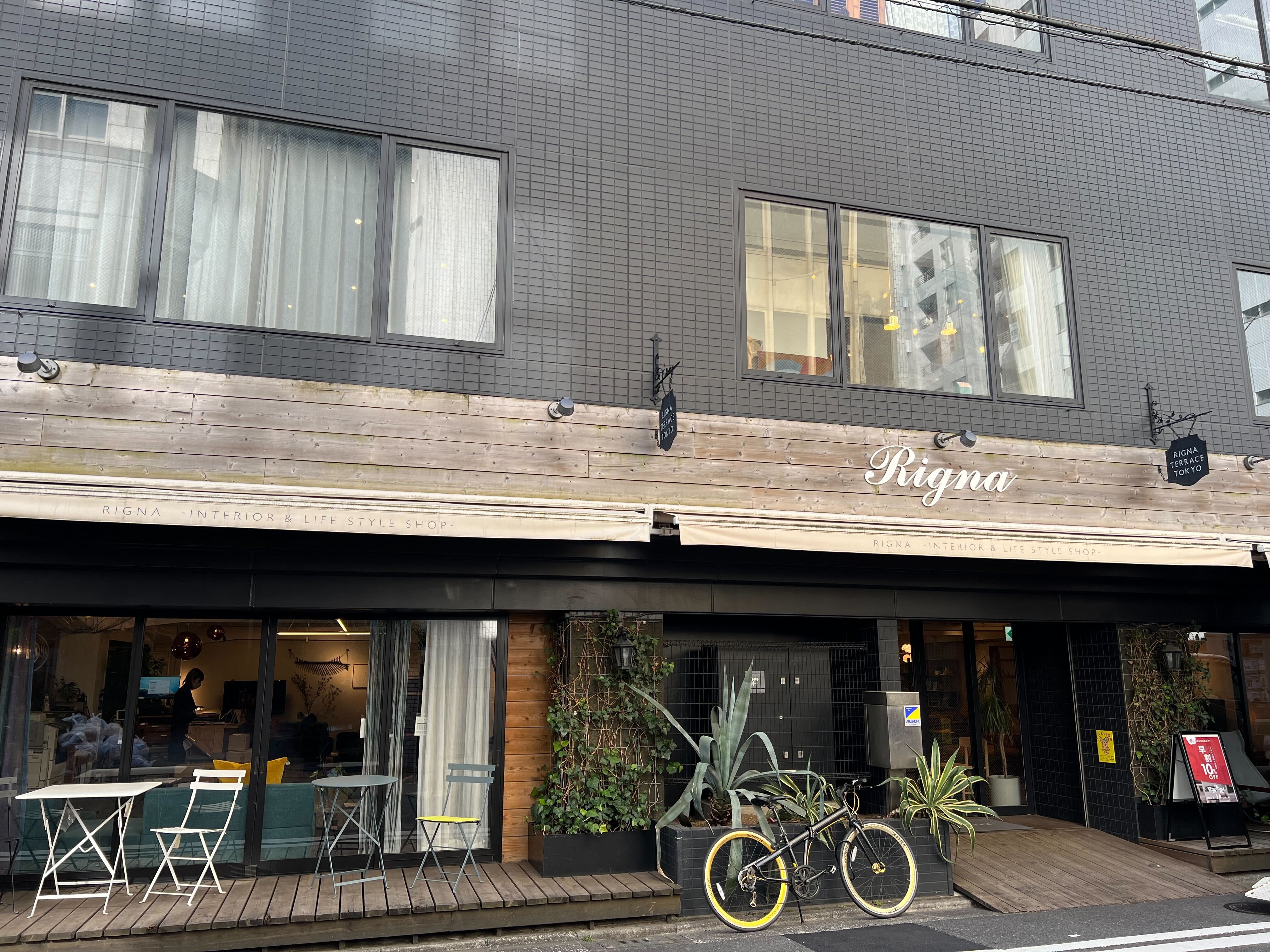 木目調のおしゃれなお店の前に観葉植物や自転車が置かれている