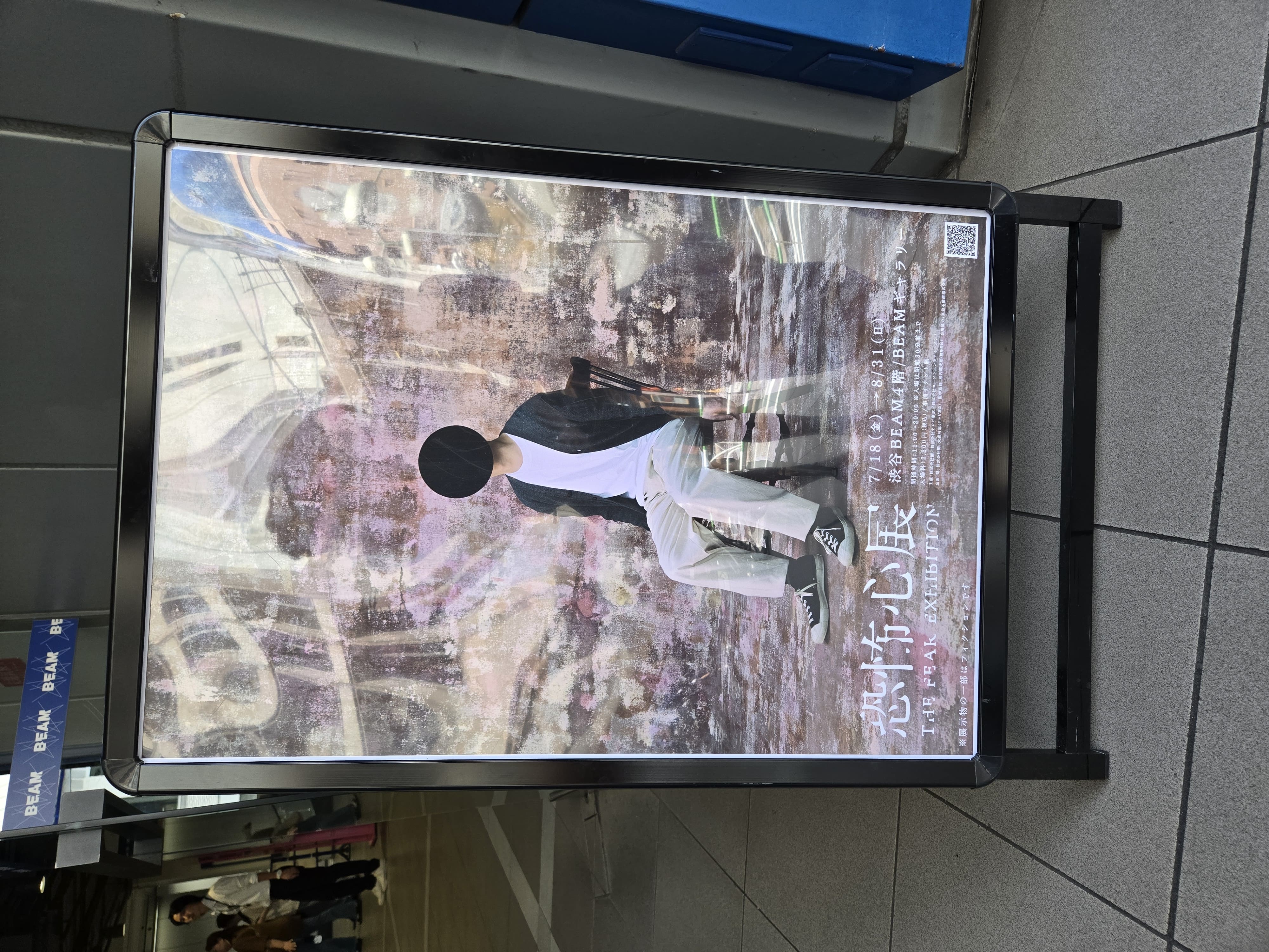 恐怖心展の看板。椅子に座った男性の顔が黒い丸で塗りつぶされている。