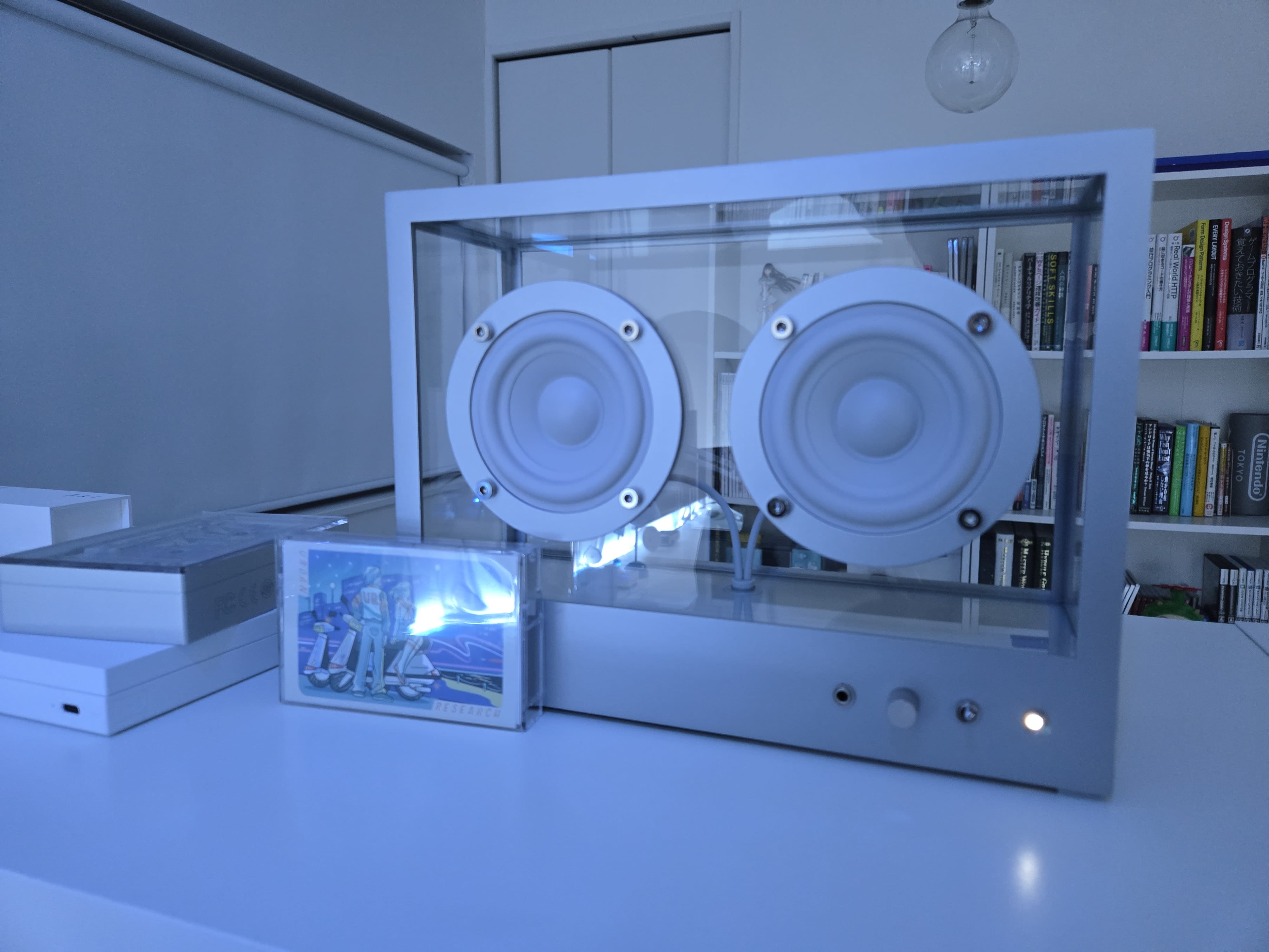 全体的に青いライティングの部屋の中に Transparent Small Speaker がカセットテープと共に置かれている。