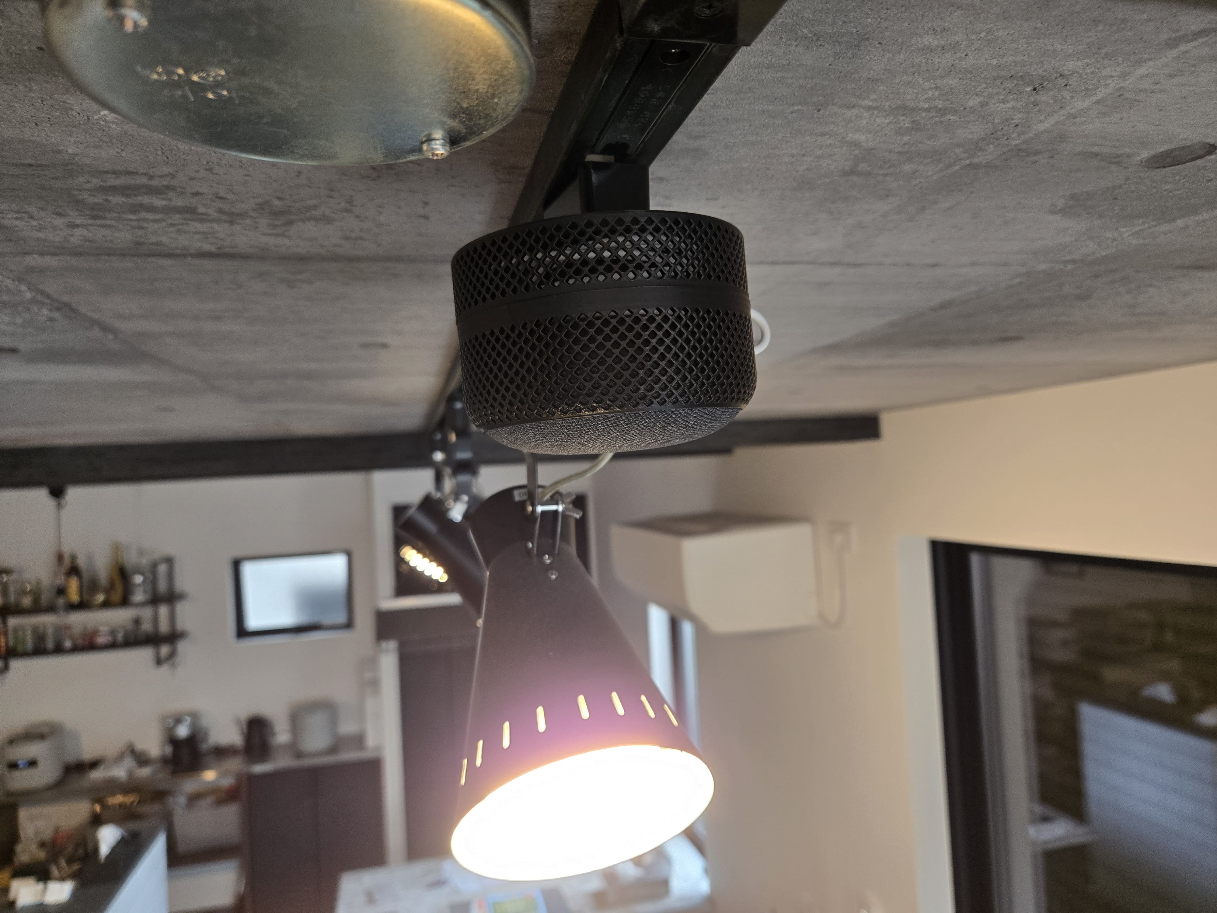 ダクトレールに網目状のケースに収まった Google Nest Mini が装着されている。