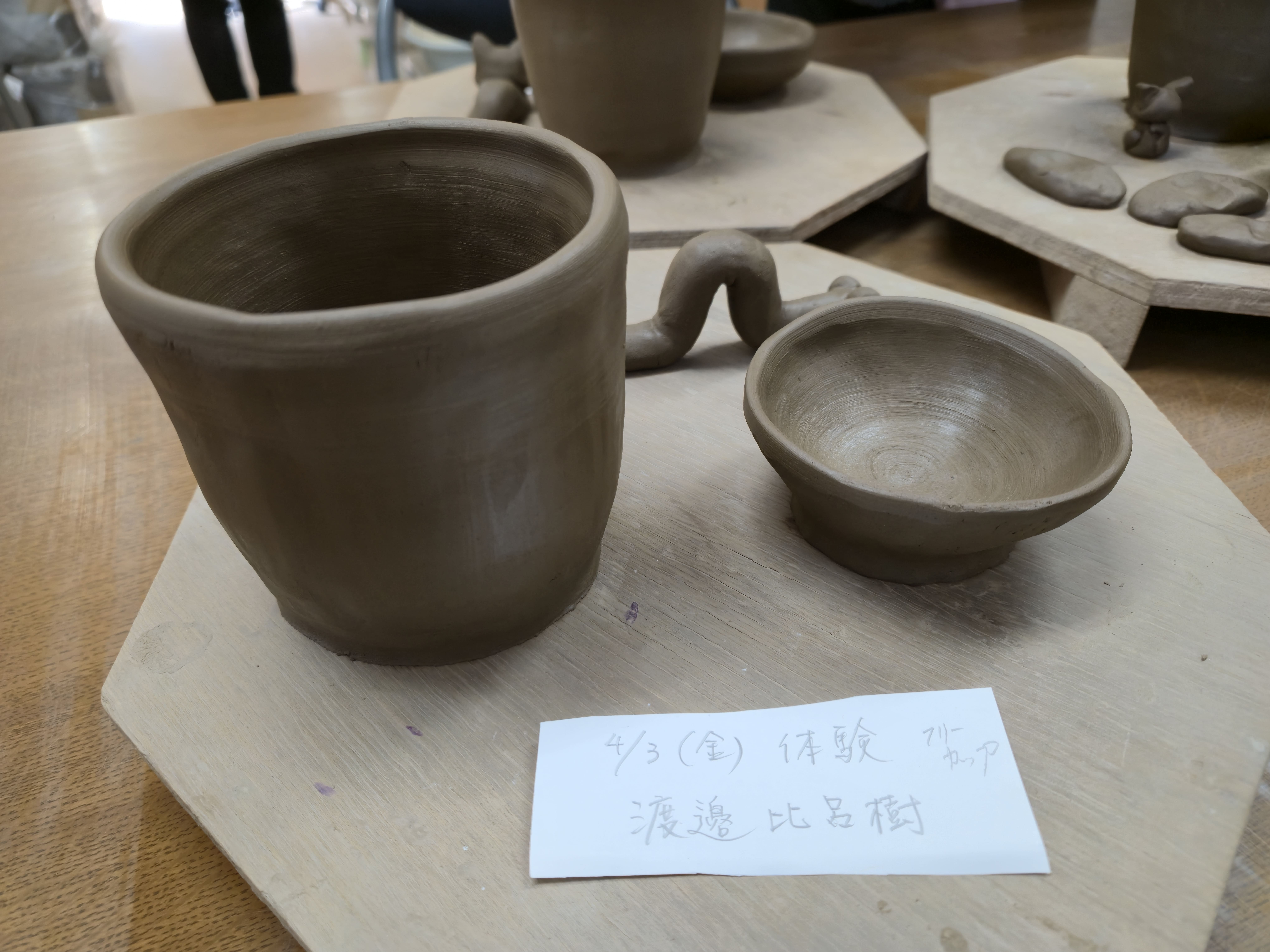 手びねりの陶芸で作った焼かれる前のカップや小皿が並べられている。