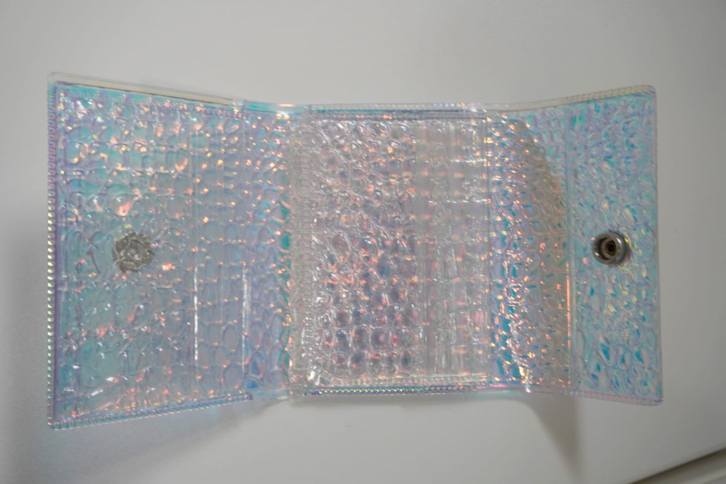 開くとこんな感じ。半透明なので、お金やカードを入れるとわりと透けて見える。 半透明のビニールの小型の財布を開いた状態。